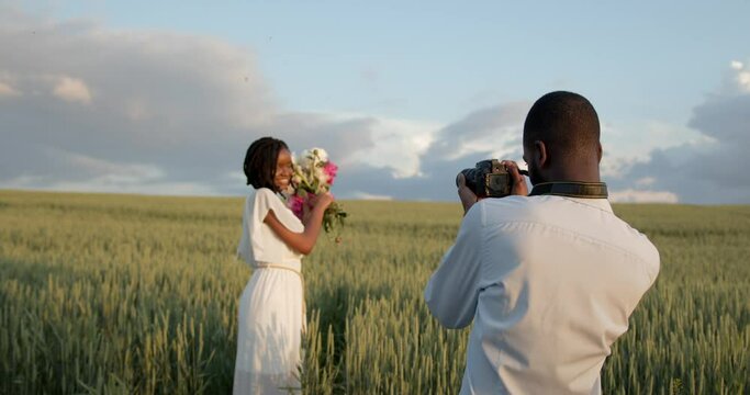 Happy couple with camera at summer field