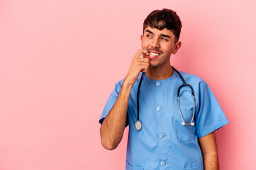 Young mixed race nurse man isolated on pink background relaxed thinking about something looking at a copy space.