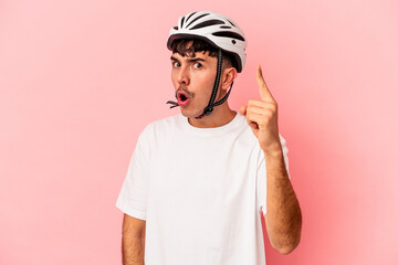 Young mixed race man wearing a helmet bike isolated on pink background having an idea, inspiration concept.