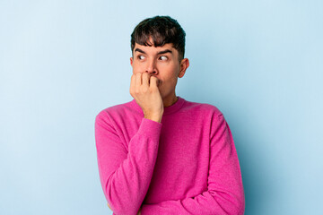 Young mixed race man isolated on blue background biting fingernails, nervous and very anxious.