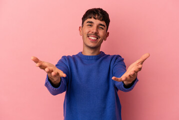 Fototapeta premium Young mixed race man isolated on pink background showing a welcome expression.