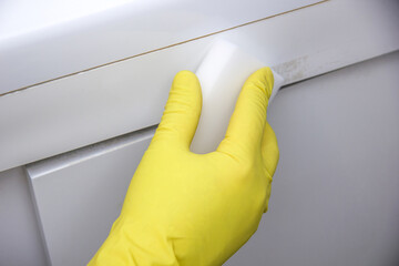 A gloved hand rubs a melamine sponge over the bathroom. Cleaning concept - obrazy, fototapety, plakaty