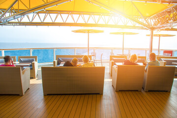 People are sitting in armchairs and looking at the sea.The liner in the open ocean, a place to relax, tables and umbrellas on the deck. Ship resting place