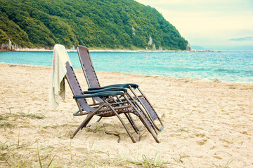 Two wicker chairs stand on the sand on the shore of the lagoon. Relaxation and relaxation on a tropical beach with sea and ocean views.