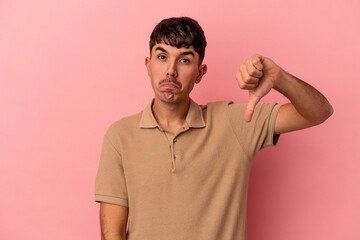 Young mixed race man isolated on pink background showing a dislike gesture, thumbs down....