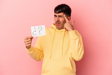 Young mixed race man holding a question placard isolated on pink background