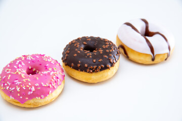 Close up of three different kind of donuts on white background.