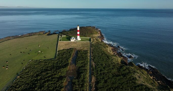 an aerial view of tarbat ness lighthouse on easter ross in the highlands of scotland near inverness showing blue sky and calm seas with the lighthouse dominating the scene and rocks