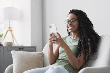 Young woman using smartphone at home. Mixed race girl looking at mobile phone. Communication,...
