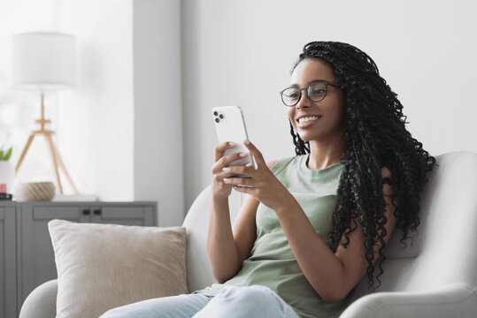 Young woman using smartphone at home. Mixed race girl looking at mobile phone. Communication, social distancing, connection, mobile apps, technology, lifestyle concept