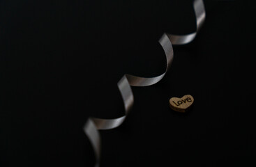 Silver ribbon and heart on black background