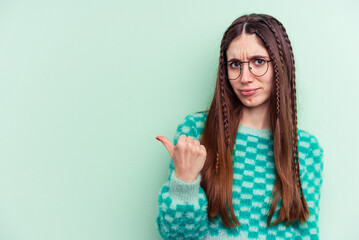 Young caucasian woman isolated on green background shocked pointing with index fingers to a copy space.