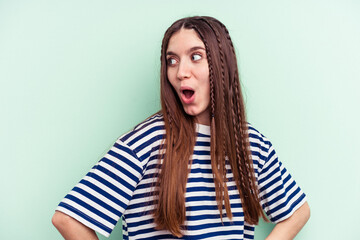 Young caucasian woman isolated on green background looks aside smiling, cheerful and pleasant.