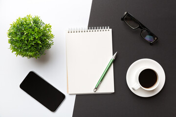 Modern office desk table with notebook, smartphone and other supplies with cup of coffee. Blank notebook page for you design. Top view, flat lay