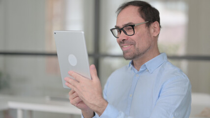 Video Call on Tablet by Middle Aged Man in Office