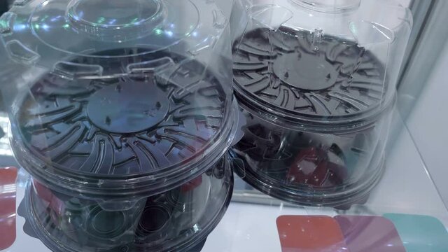 Plastic new transparent, with brown colored bottom containers for cace packaging on conveyor line in food industry. Shot in motion. Closeup