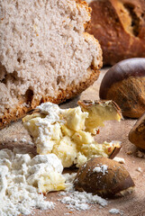 A loaf of bread made with chestnut flour with whole chestnuts on a wooden chopping board.