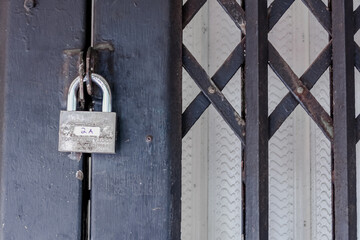 Silver metal padlock hanging on the locked black iron entrance