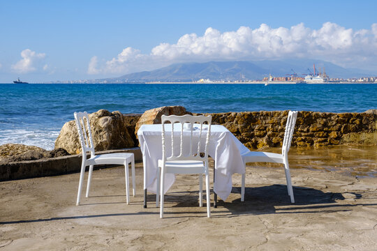 Mesa y sillas con mantel blanco junto al mar
