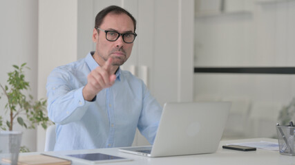 Middle Aged Man with Laptop Pointing at the Camera