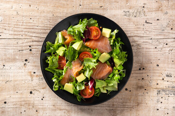 Salmon and avocado salad on rustic wooden table	