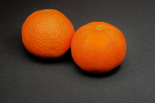 Cl&eacute;mentines en gros plan sur un fond noir. C'est un agrume, fruit du cl&eacute;mentinier, un arbre hybride de la famille des rutac&eacute;es, issu du croisement entre un mandarinier et un oranger