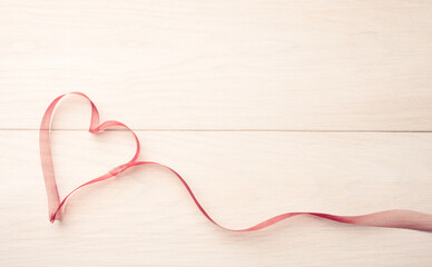 Ribbon in the shape of a heart on a light wooden table, Valentines Day or love concept, space for...