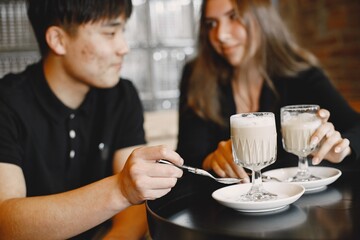 Young couple holding a cups of cappuccino in a restaurant