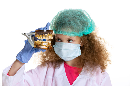 Studio shot of cute little girl, child in image of dentist doctor wearing white lab coat and gloves isolated on white studio background