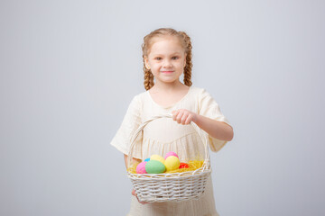 a little girl holds a basket with Easter eggs on a white background, isolated