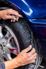Man mechanic installing the front bumper with his hands of a blue car exterior at the auto repair garage