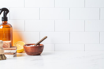 Eco home cleaning. Natural brushes, sponges and organic cleaning products on white kitchen table. Zero waste concept.