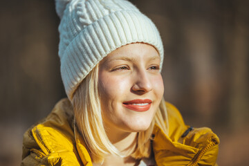 Portrait of happy blonde woman in park in autumn. She is enjoying nature. Beautiful smiling young woman in wintertime outdoor. Winter concept. Happy Blond Woman Warming
