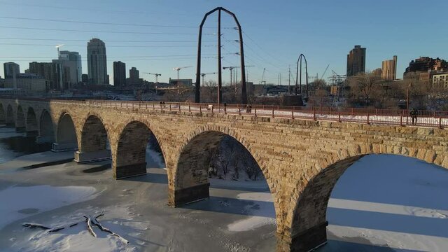 Aerial view of people at Stone Arch bridge in Minneapolis, MN during golden hour winter afternoon