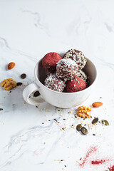 Raw vegan dessert. Energy balls. Truffles made from nuts, seeds, cocoa, dates and superfood powders, white marble background.