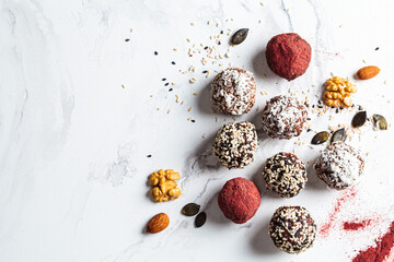 Fototapeta na wymiar Raw vegan dessert. Energy balls. Truffles made from nuts, seeds, cocoa, dates and superfood powders, white marble background.