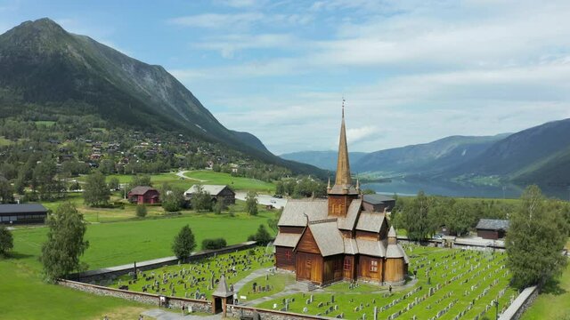 Aerial view of the Lom Stave Church and mountains, summer in Norway - tracking, drone shot