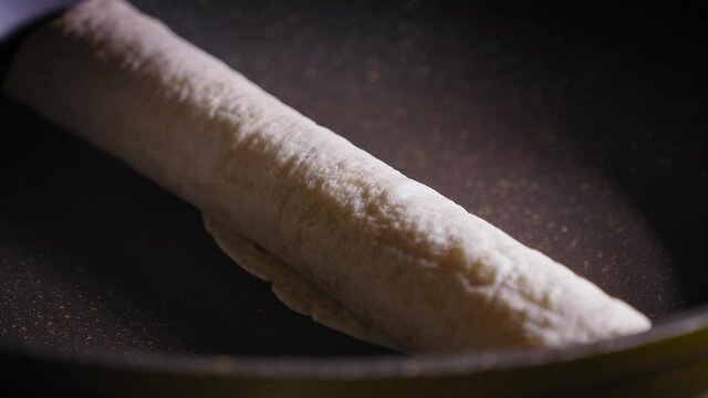 Heating Rolled Hot dog Tortilla In A Skillet. close up
