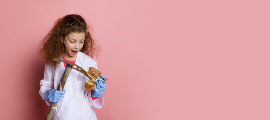 Flyer. Comic portrait of little girl, child in image of dentist doctor wearing white lab coat and gloves isolated on pink studio background