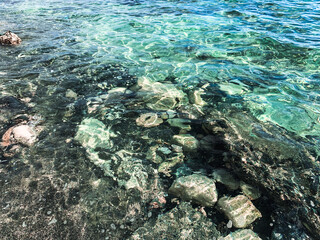 Transparent sea surface, lagoon, pebbles and stones, ripples on the sea surface