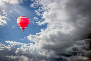 a red hot air balloon soaring into clouds of a summer storm