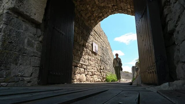 Video with a woman walks around the ruins of the old medieval fortress Ovech near Provadia, Bulgaria and enjoys the view from above. Low-angle view.