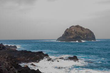 the sea hits the rocks and the islet hard