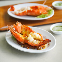 Grilled river prawn. Fine dining of a charcoal grilled lobster with soft focus served with seafood sauce on the mini bowl.