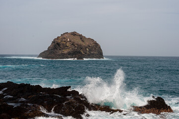 the sea hits the rocks and the islet hard