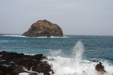 the sea hits the rocks and the islet hard