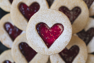 Macro close up image of Linzer cookie. Heart shape biscuit with raspberry red jam. Blurred background. Valentine, love and romance food concept image with copy space