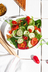 Vegetarian salad with cucumber, tomato and spinach in a plate