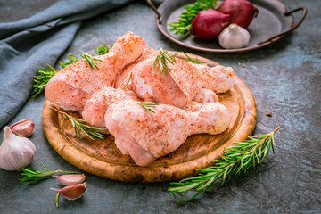 Raw uncooked chicken legs, drumsticks on wooden board, meat with ingredients for cooking