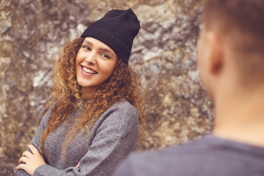 Beautiful hipster woman with knit hat flirting with friend